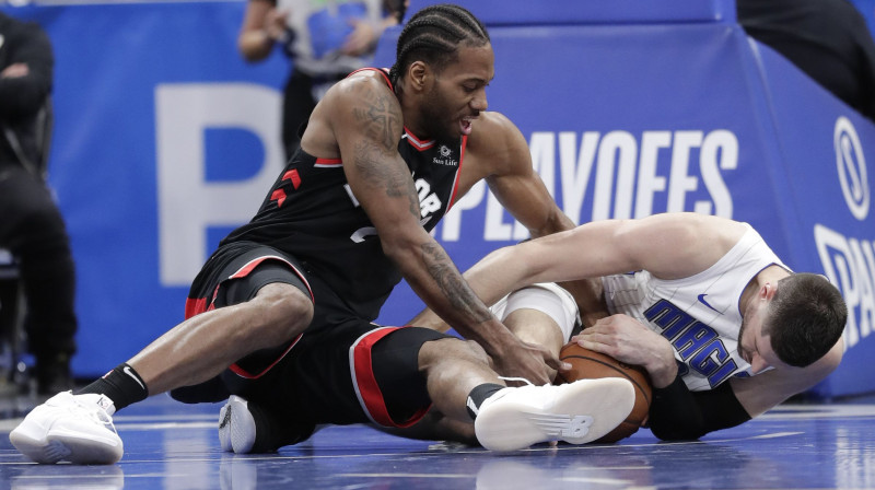 "Raptors" zvaigzne Kavai Lenards cīnās par bumbu ar "Magic" spēlētāju Nikolu Vučeviču. Foto: AP/Scanpix